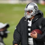 DENVER, CO - JANUARY 03: Las Vegas Raiders quarterback Marcus Mariota (8) holds a ball in the bench area during a game b