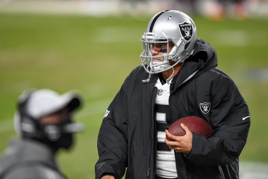 DENVER, CO - JANUARY 03: Las Vegas Raiders quarterback Marcus Mariota (8) holds a ball in the bench area during a game b