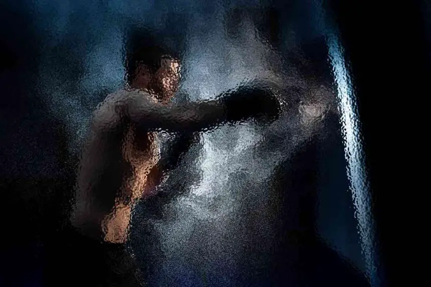 Ein verschwommenes, künstlerisches Bild eines Boxers mitten im Schlag. Der Boxer ist oben ohne und trägt Boxhandschuhe, während er auf eine Lichtquelle einschlägt. Der Hintergrund ist dunkel, mit rauchigen, dynamischen Effekten, die die Bewegung umgeben und eine dramatische und intensive Atmosphäre erzeugen. Diese Beschreibung wurde mit der FootballR KI automatisch generiert.