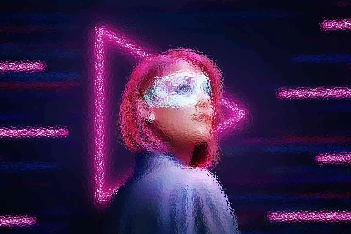 Eine Person mit pinkfarbenen Haaren trägt eine futuristische Schutzbrille und blickt nach oben. Sie steht vor einem neonpinken Playbutton-Symbol und Neonlinien auf dunklem Hintergrund. Das Bild hat einen digitalen, leicht verschwommenen Effekt, der ihm eine Sci-Fi-Atmosphäre verleiht. Diese Beschreibung wurde mit der FootballR KI automatisch generiert.