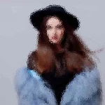 Eine Person mit langen Haaren, die einen schwarzen Hut und einen blauen, flauschigen Mantel trägt, steht vor einem hellgrauen Hintergrund. Das Bild ist absichtlich unscharf, wodurch ein impressionistischer Effekt entsteht, detaillierte Gesichtszüge verdeckt und die Gesamtform und -farben hervorgehoben werden. Diese Beschreibung wurde mit der FootballR KI automatisch generiert.