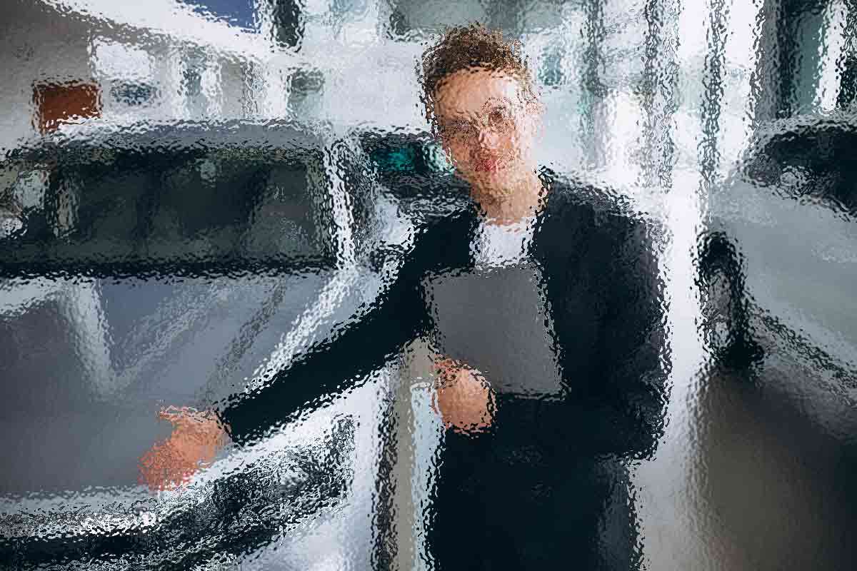 Eine Person im Anzug deutet mit offener Handfläche auf ein Auto und steht in einem hellen, modernen Ausstellungsraum. In der anderen Hand hält sie ein Tablet. Das Bild ist absichtlich unscharf, sodass feinere Details des Autos und der Umgebung nicht zu erkennen sind. Diese Beschreibung wurde mit der FootballR KI automatisch generiert.