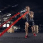 Eine Person in Sportkleidung trainiert in einem Fitnessstudio mit Battle Ropes. Die Person hockt und bewegt die roten Seile energisch in einem schwach beleuchteten Raum, der von sanften Deckenlampen erhellt wird. Diese Beschreibung wurde mit der FootballR KI automatisch generiert.