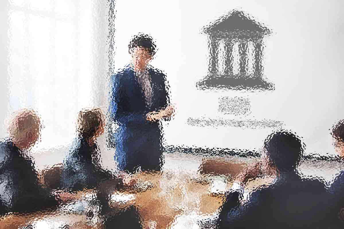 Unscharfes Bild eines Geschäftstreffens, bei dem eine Person im Anzug vor vier sitzenden Kollegen einen Vortrag hält. Auf einem Bildschirm oder einer Wand im Hintergrund wird ein großes Symbol angezeigt, das an ein klassisches Gebäude mit Säulen erinnert. Dies deutet darauf hin, dass der Fokus auf Finanzen, Unternehmensführung oder Rechtsfragen liegt. Diese Beschreibung wurde mit der FootballR KI automatisch generiert.