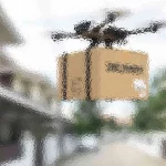 Eine Drohne mit einem Kartonpaket fliegt über eine verschwommene Vorstadtstraße. Das Paket ist braun und die Drohne hat mehrere Propeller. Im Hintergrund sind Häuser und Grünflächen mit einem Unschärfeeffekt zu sehen, der auf Bewegung oder einen Kamerafilter hindeutet. Diese Beschreibung wurde mit der FootballR KI automatisch generiert.