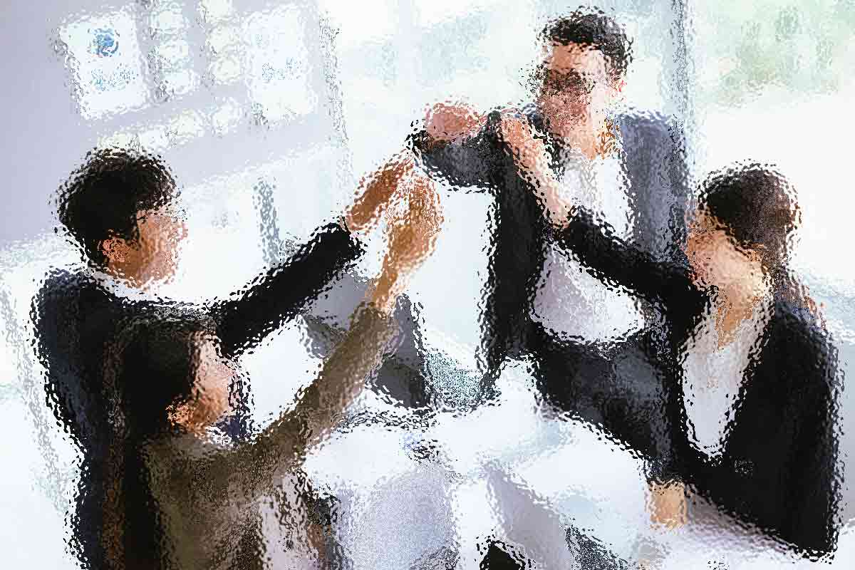 Eine Gruppe von vier Personen in Business-Kleidung feiert ein erfolgreiches Meeting mit einem High-Five an einem Tisch in einem hellen Büro. Sie wirken fröhlich und enthusiastisch. Im Hintergrund sind verschwommene Diagramme und Fenster zu sehen, durch die natürliches Licht einfällt. Diese Beschreibung wurde mit der FootballR KI automatisch generiert.