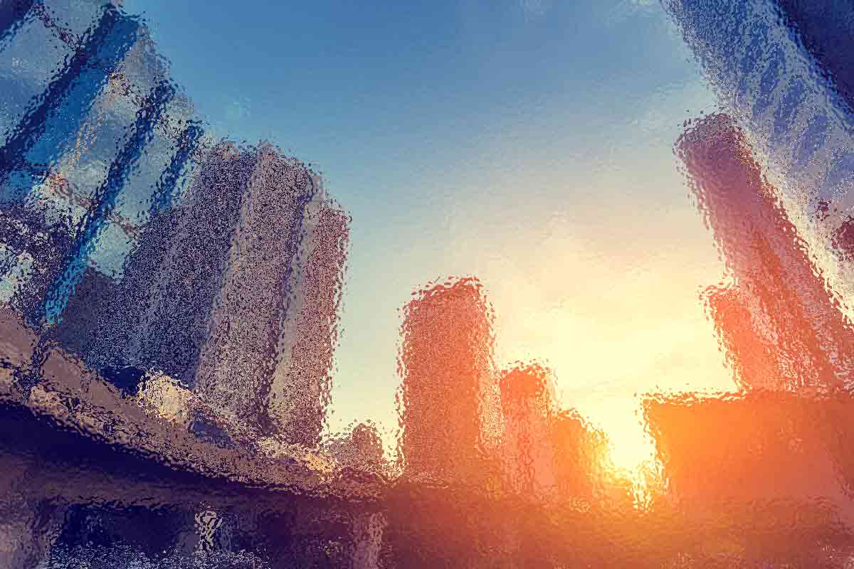 Abstrakte Stadtlandschaft bei Sonnenuntergang mit verschwommenen, verzerrten Wolkenkratzern. Die Sonne geht am Horizont unter und wirft einen orangefarbenen Schimmer auf die Gebäude. Der Himmel wechselt von Blau zu einem warmen Gelb und Orange und schafft so eine verträumte, surreale Atmosphäre. Diese Beschreibung wurde mit der FootballR KI automatisch generiert.