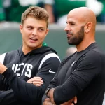 FootballR - NFL - Zwei Männer, Zach Wilson und Robert Saleh, reden bei einem Footballspiel miteinander.