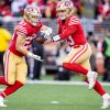 FootballR - NFL - RTL NFL Woche 15 - Zwei Spieler der San Francisco 49ers, Brock Purdy und Christian McCaffrey, laufen mit dem Ball.