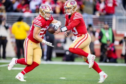 FootballR - NFL - RTL NFL Woche 15 - Zwei Spieler der San Francisco 49ers, Brock Purdy und Christian McCaffrey, laufen mit dem Ball.