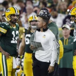 Quarterback Aaron Rodgers spricht mit Packers Headcoach Matt LaFleur, Jordan Love hört zu