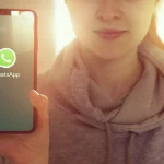 KYIV, UKRAINE-JANUARY, 2020: Whatsapp on Mobile Phone Screen. Young Girl Showing Smartphone Screen with Whatsapp on it while Looking at the Camera. Focus on Smartphone.