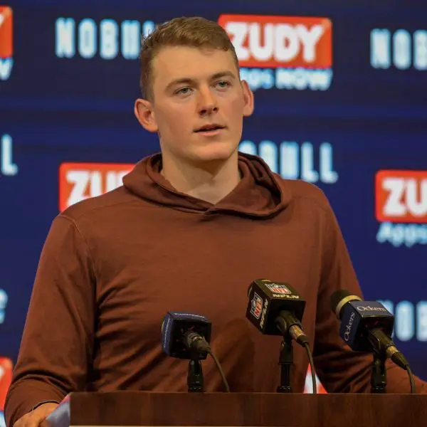 FootballR - NFL - New England Patriots QB Mac Jones steht bei einer Pressekonferenz vor einem Mikrofon.