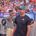 FootballR - NFL - Aaron Rodgers Rückkehr - Ein Mann mit Hut steht vor einer Menschenmenge.