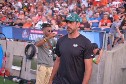 FootballR - NFL - Aaron Rodgers Rückkehr - Ein Mann mit Hut steht vor einer Menschenmenge.