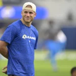 FootballR - NFL - Ein Mann in einem blauen Hemd (Cooper Kupp) steht auf einem Fitnessfeld.