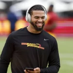 FootballR - NFL - Ein USC-Quarterback namens Caleb Williams, der Kopfhörer trägt und auf dem Spielfeld lächelt.