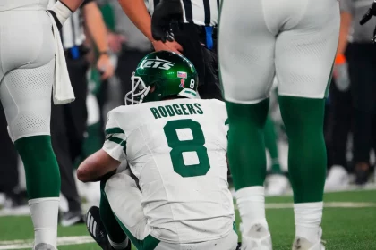 FootballR - NFL - Ein Footballspieler, Aaron Rodgers, sitzt verletzt am Boden draußen.