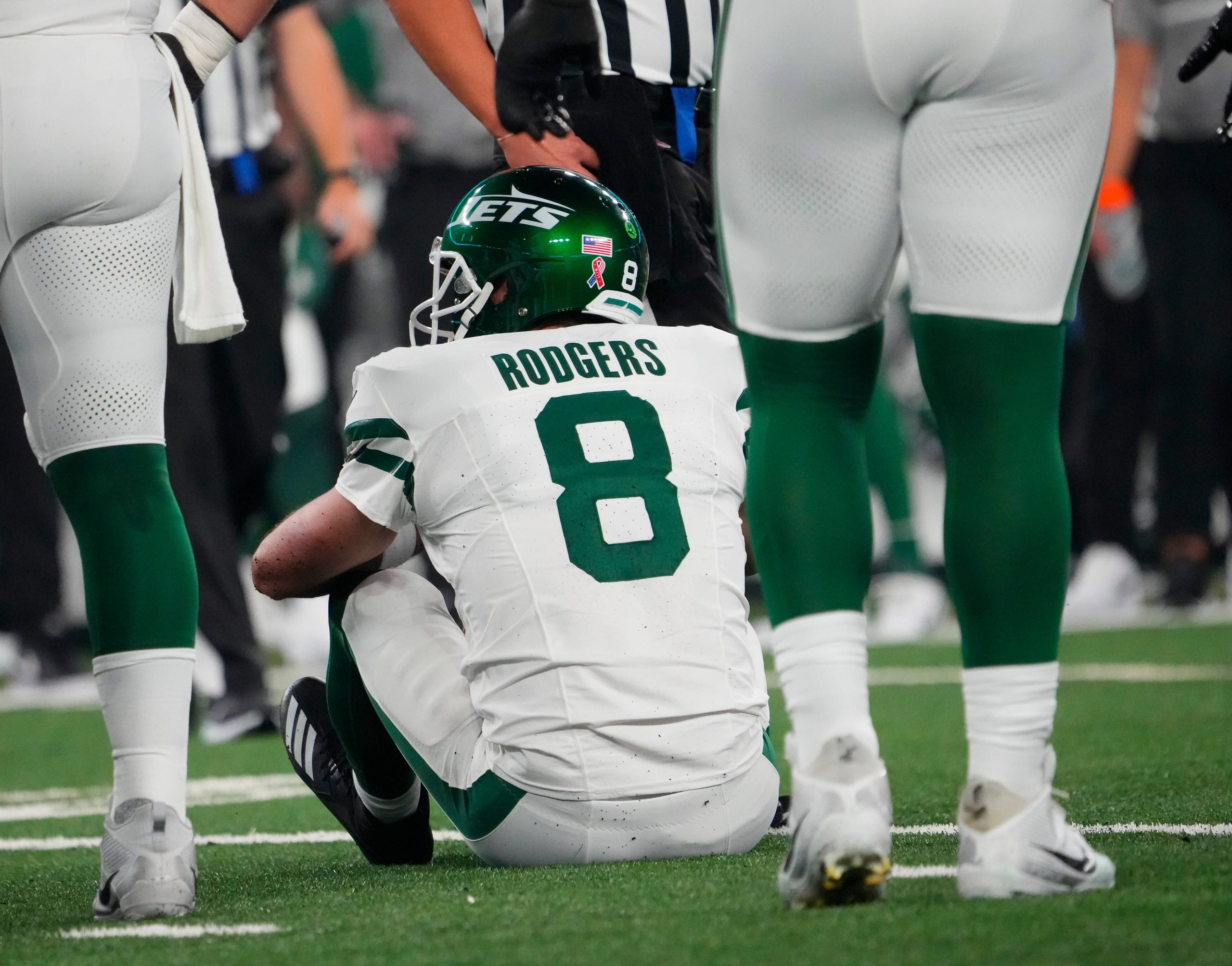 FootballR - NFL - Ein Footballspieler, Aaron Rodgers, sitzt verletzt am Boden draußen.