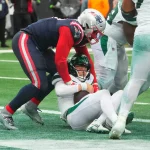FootballR - NFL - Bei einer enttäuschenden Niederlage gegen die Patriots wird Zach Wilson von einem anderen Spieler angegriffen.
