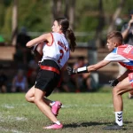 FootballR - NFL - Eine Gruppe Mädchen spielt Flag-Football auf einem Feld.