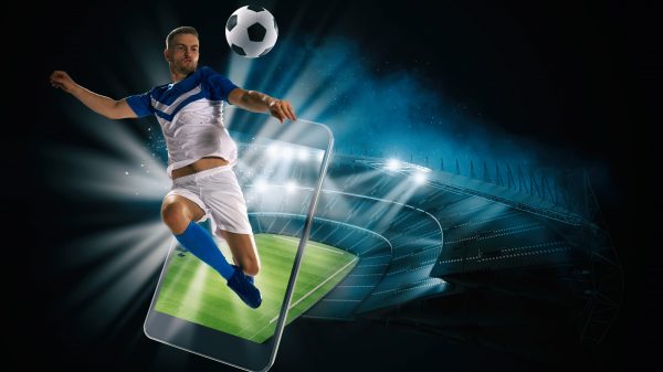 Soccer player, cellphone and ball on a stadium