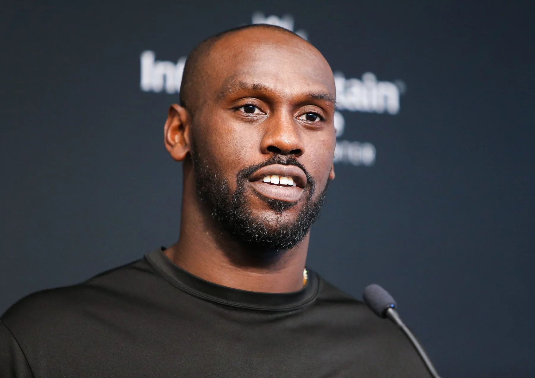 FootballR - NFL - Chandler Jones - Ein Mann in einem schwarzen Hemd steht bei der Pressekonferenz der Las Vegas Raiders vor einem Mikrofon.