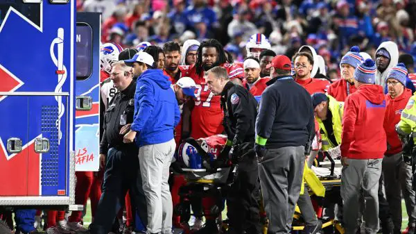 FootballR - NFL - Buffalo Bills RB Damien Harris aus dem Krankenhaus entlassen, während eine Gruppe von Menschen auf einem Footballfeld um einen Rettungswagen her