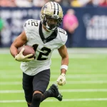 FootballR - NFL - Der Wide Receiver Chris Olave der New Orleans Saints spielt kraftvoll mit dem Ball.