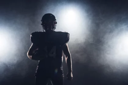 FootballR - NFL Game Pass 2024 - Die Silhouette eines Footballspielers, der einen Ball hält, vor einem dunklen Hintergrund, perfekt, um Ihr DAZN-Abo zu präsentieren.