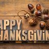 FootballR - NFL - Das Wort Happy Thanksgiving auf einem Holztisch, umgeben von NFL Thanksgiving-Spiele und hochkarätigen Halftime Shows.