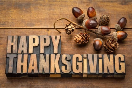 FootballR - NFL Thanksgiving 2025 - Das Wort Happy Thanksgiving auf einem Holztisch, umgeben von NFL Thanksgiving-Spiele und hochkarätigen Halftime Shows.