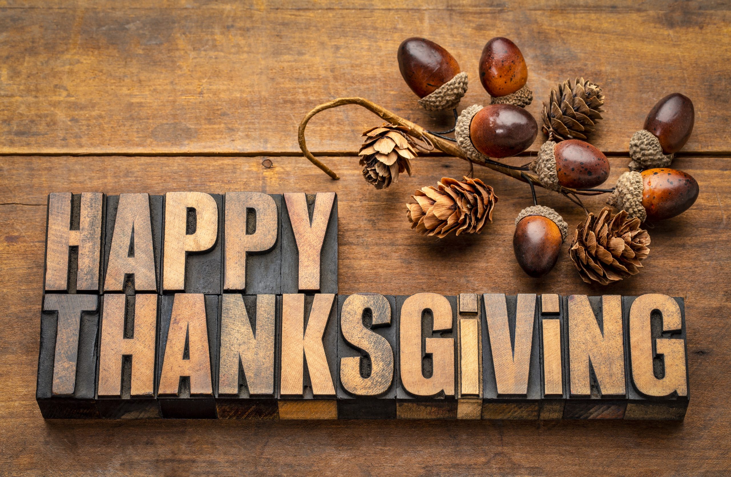 FootballR - NFL Thanksgiving - Das Wort Happy Thanksgiving auf einem Holztisch, umgeben von NFL Thanksgiving-Spiele und hochkarätigen Halftime Shows.