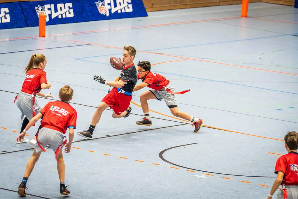 FootballR - NFL - Eine Gruppe von Kindern spielt auf einem Platz eine Partie Flag Football und stellt ihr Können im NFL FLAG Football unter Beweis.