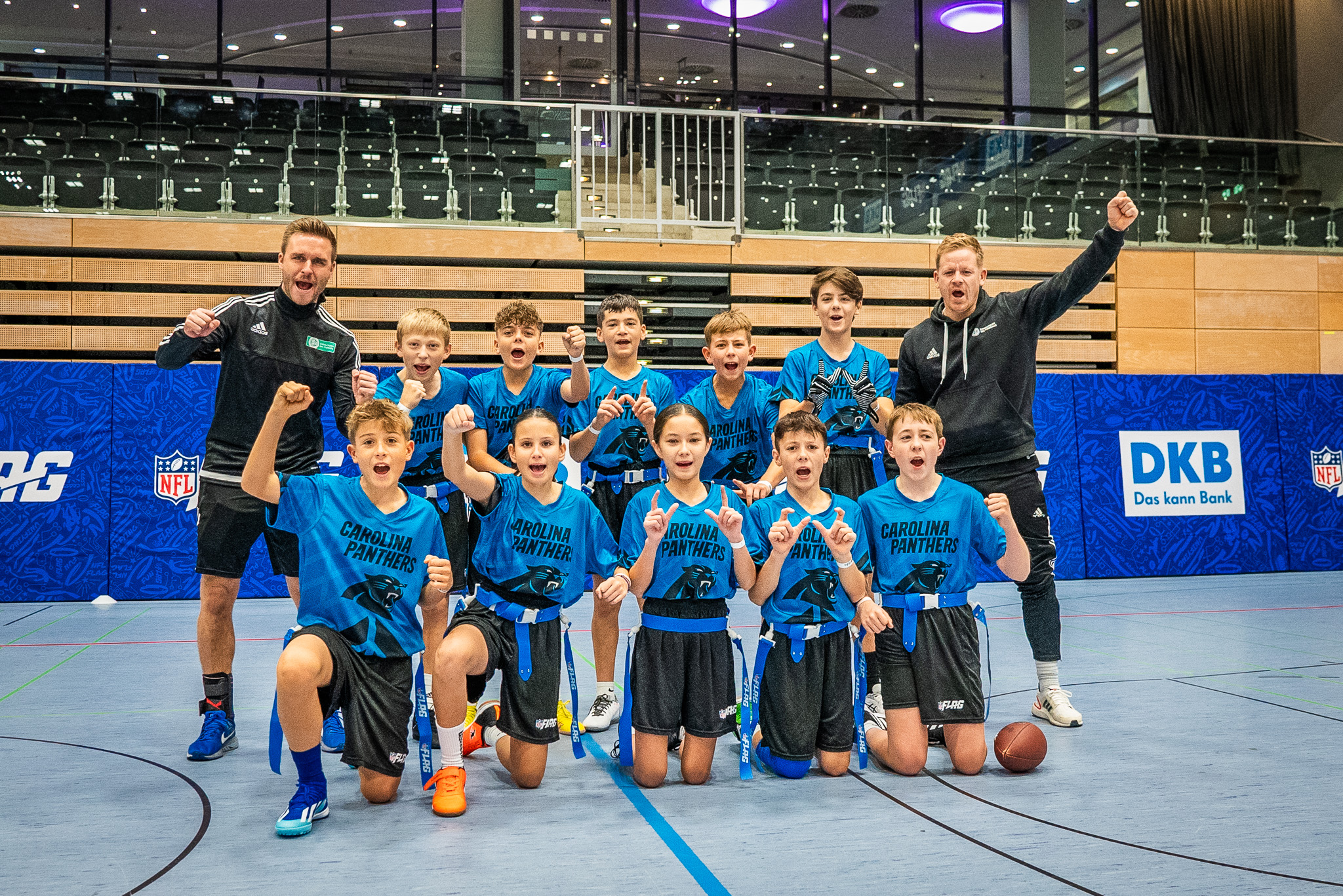 FootballR - NFL - Eine Gruppe von Kindern der Taufkirchner Schule posiert während des Deutschland-Finales der NFL FLAG Football für ein Foto auf einem Basketballplatz.