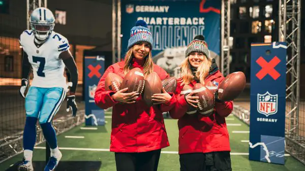 FootballR - NFL - Zwei Frauen halten während der Weihnachtszeit Fußbälle auf einer NFL-Bühne.