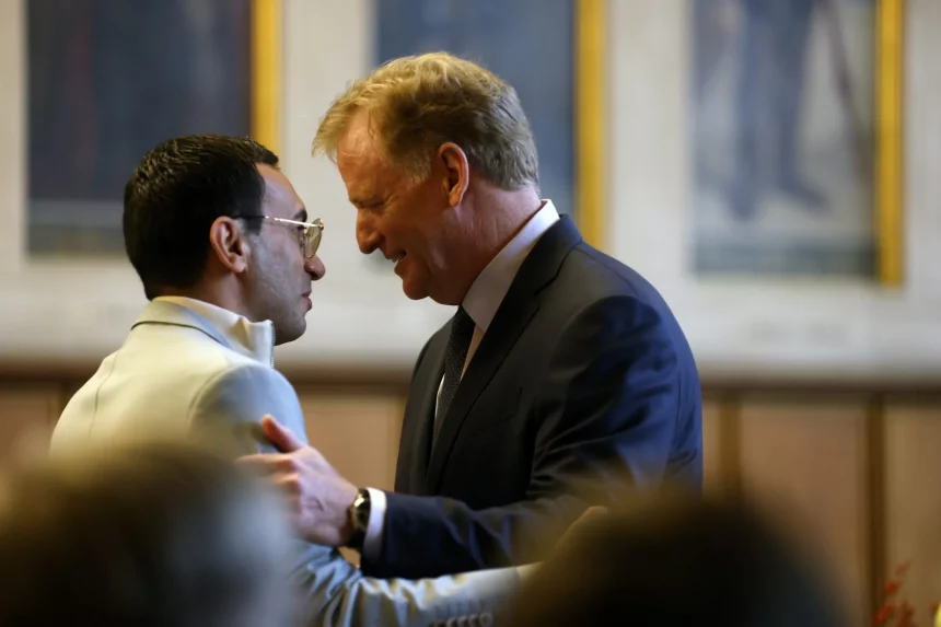 FootballR - NFL - Roger Goodell, der Commissioner der NFL, umarmt bei einer Veranstaltung in Frankfurt einen anderen Mann in Anzug und Krawatte.