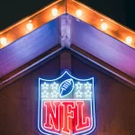 FootballR - NFL am Düsseldorfer Weihnachtsmarkt - Das NFL-Logo leuchtet während der Weihnachtszeit an der Seite eines Gebäudes.