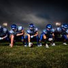 FootballR - NFL - Eine Gruppe American-Football-Spieler posiert vor einem dunklen Himmel.