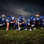 FootballR - NFL - Eine Gruppe American-Football-Spieler posiert vor einem dunklen Himmel.