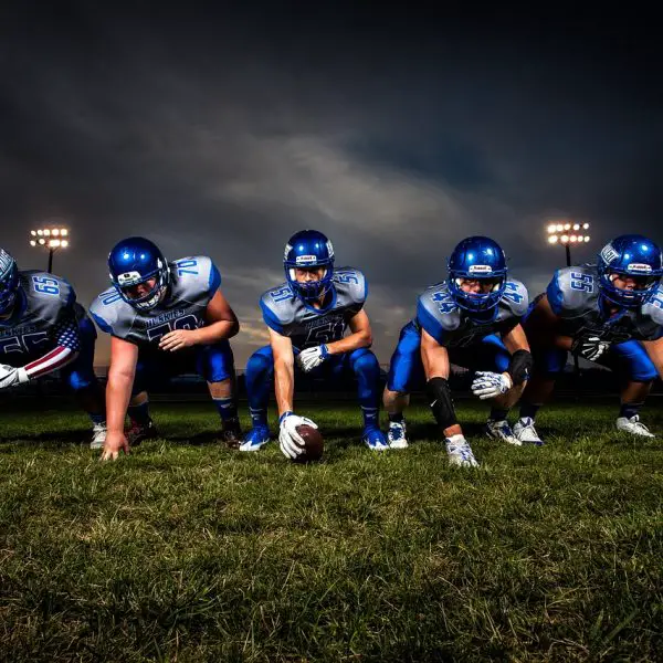 FootballR - NFL - Eine Gruppe American-Football-Spieler posiert vor einem dunklen Himmel.