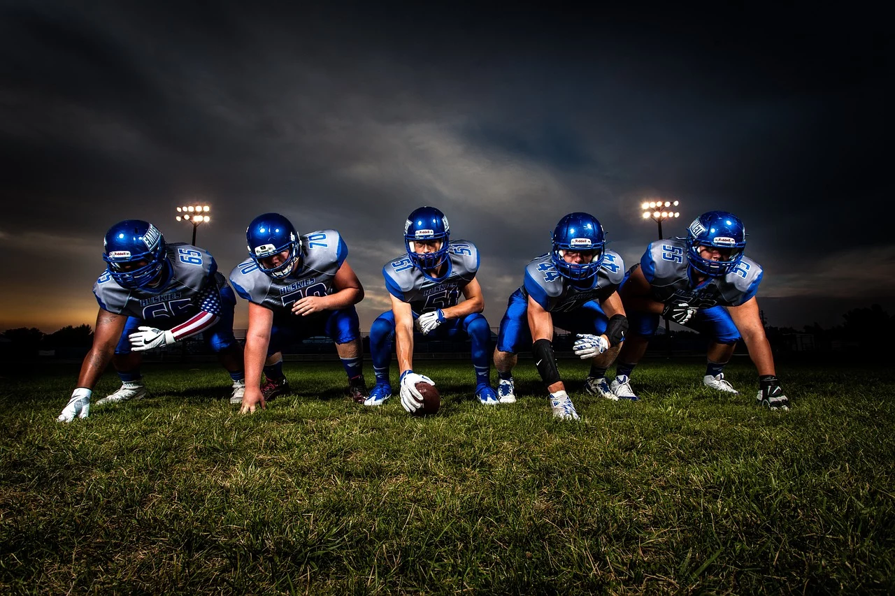 FootballR - NFL - Eine Gruppe American-Football-Spieler posiert vor einem dunklen Himmel.