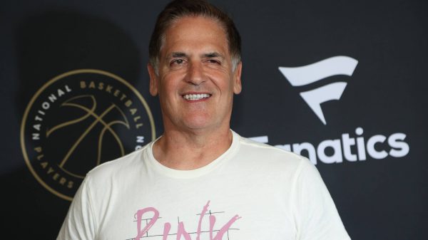 FootballR - NFL - NBA-Besitzer Mark Cuban, bekannt für seine aktive Präsenz in den sozialen Medien, posiert lässig auf einem schwarzen Teppich und trägt ein rosa T-Shirt.