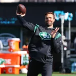 FootballR - NFL - Quarterback Joe Flacco wirft einen Football auf ein Feld.