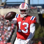 FootballR - NFL - Raiders-Cornerback Jack Jones wirft einen Football vor einer Menschenmenge.