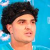 FootballR - NFL - Jaelan Phillips, ein Spieler der Miami Dolphins, mit lockigem Haar vor einem Mikrofon.