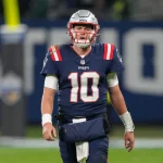 FootballR - NFL - Der Starting-Quarterback der New England Patriots, Mac Jones, läuft über das Spielfeld.