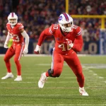 FootballR - NFL - Ein Bills-Footballspieler läuft neben Bills-Star Von Miller auf dem Spielfeld.