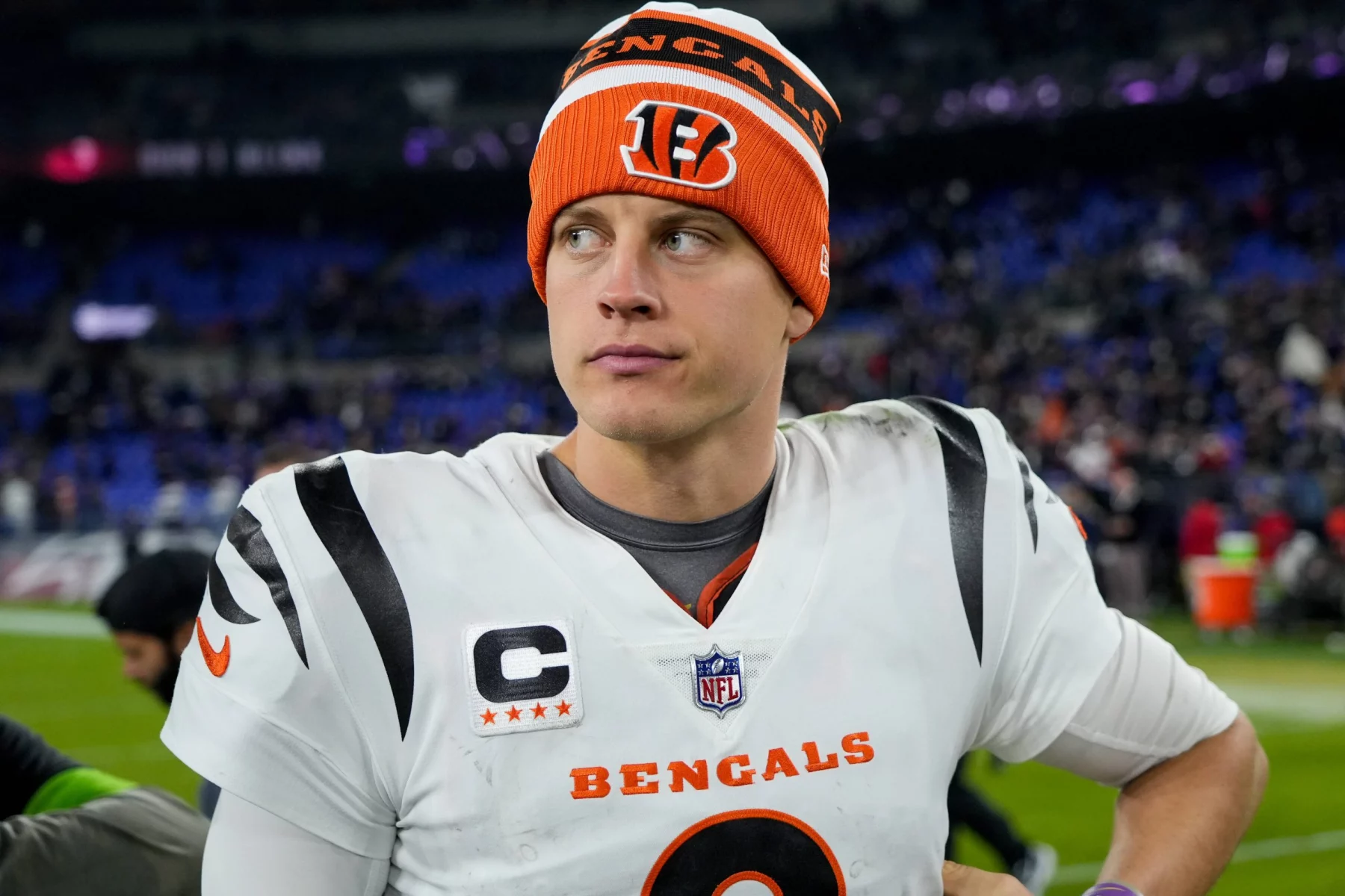 FootballR - NFL - Cincinnati Bengals Quarterback Joe Burrow in orange-weißer Uniform steht auf einem Feld.