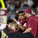 FootballR - NFL - Die Footballmannschaft der Florida State Seminoles, zu der auch der QB Jordan Travis von Florida State gehört, sitzt am Spielfeldrand und erholt sich von einer Beinverletzung (Beinverletzung), während sie Grausame (